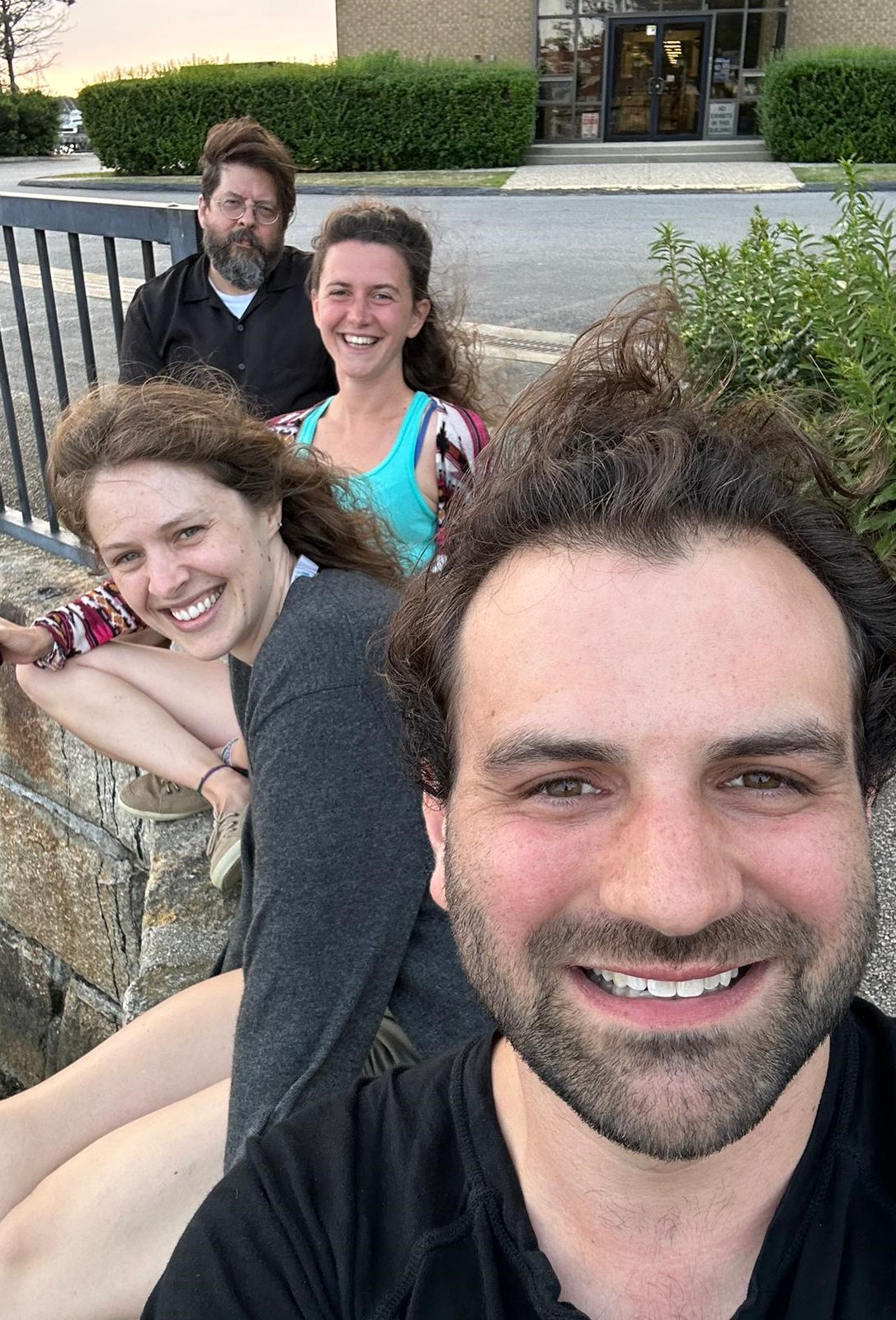 four people sitting in a row outside.