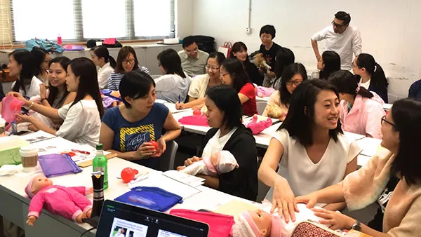 Large group of ladies studying medical baby mannequins 