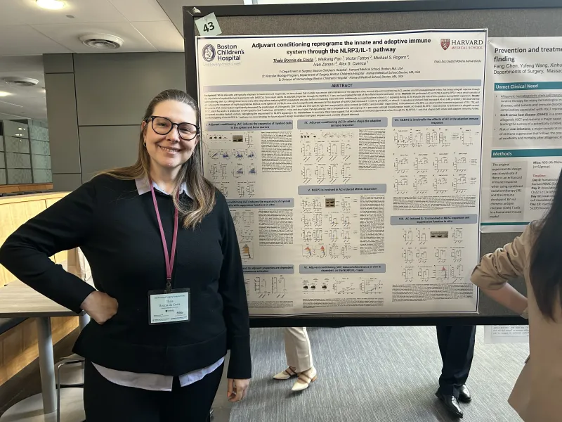 A woman stands next to her poster of her scientific presentation.