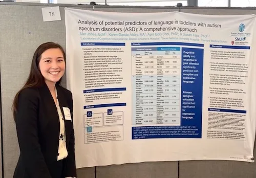 Woman with brown hair in business formal attire standing in front of a poster presentation