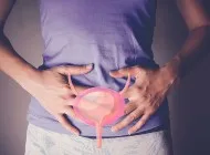 A woman holds her core and there is a drawing of a uterus on top of stomach.