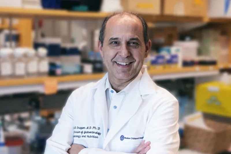Scott Snapper, a researcher, stands in his Boston Children's lab coat with his arms crossed.